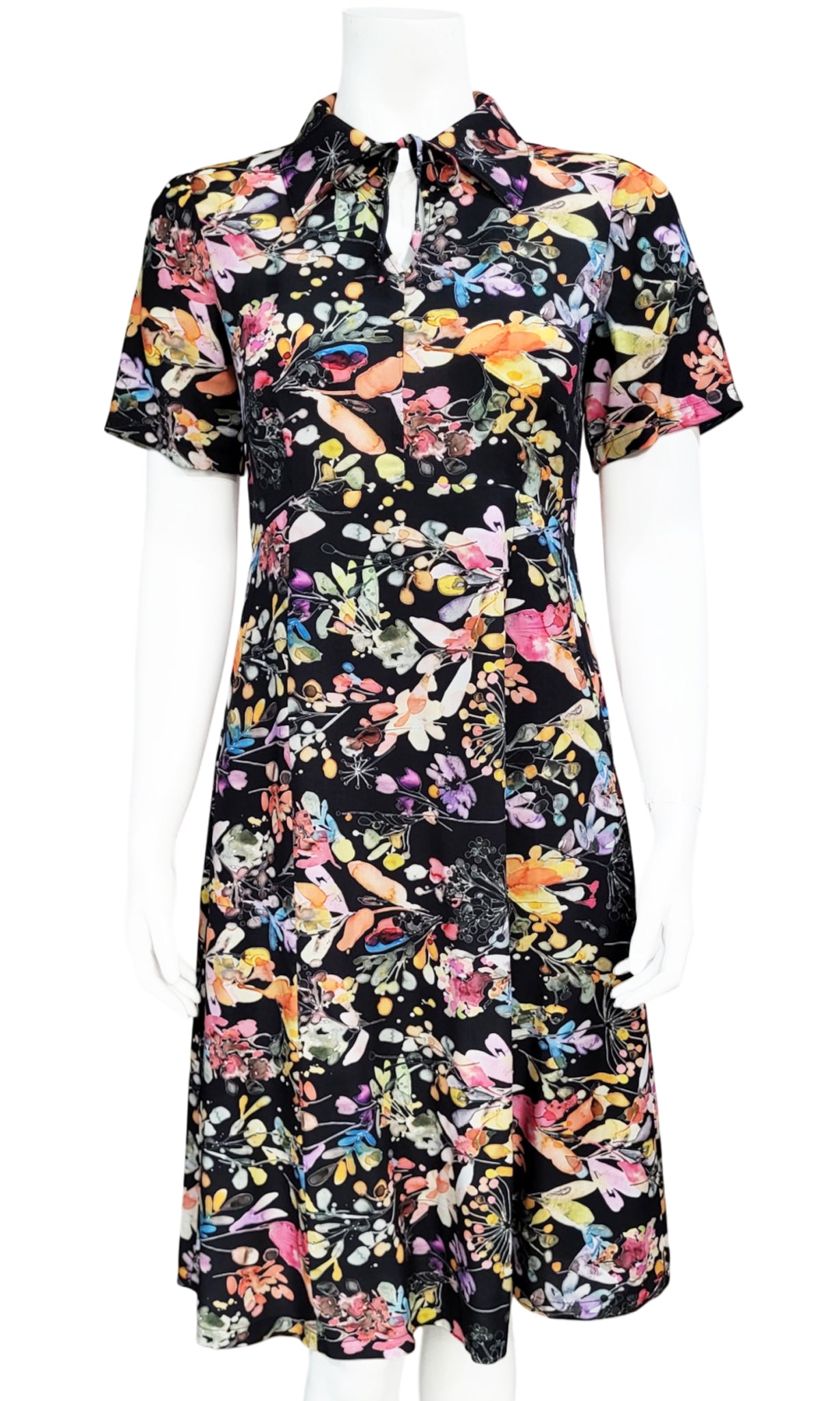 A short-sleeve collared dress with a vibrant multicolor floral print on a black background, displayed on a white mannequin against a white background.